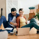 A couple sitting on a hardwood floor after buying a home in San Diego