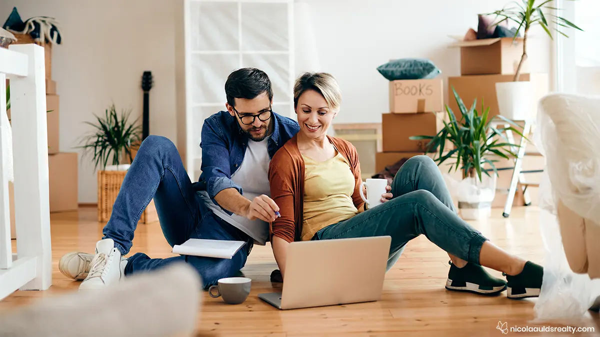 A couple sitting on a hardwood floor after buying a home in San Diego
